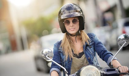 Ung kvinne kjører scooter i urbant miljø