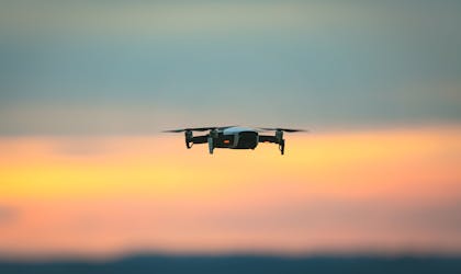 Liten DJI drone som flyr i solnedgangen