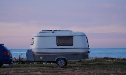 Campingvogn parkert ved kysten, med utsikt over hav og horisont